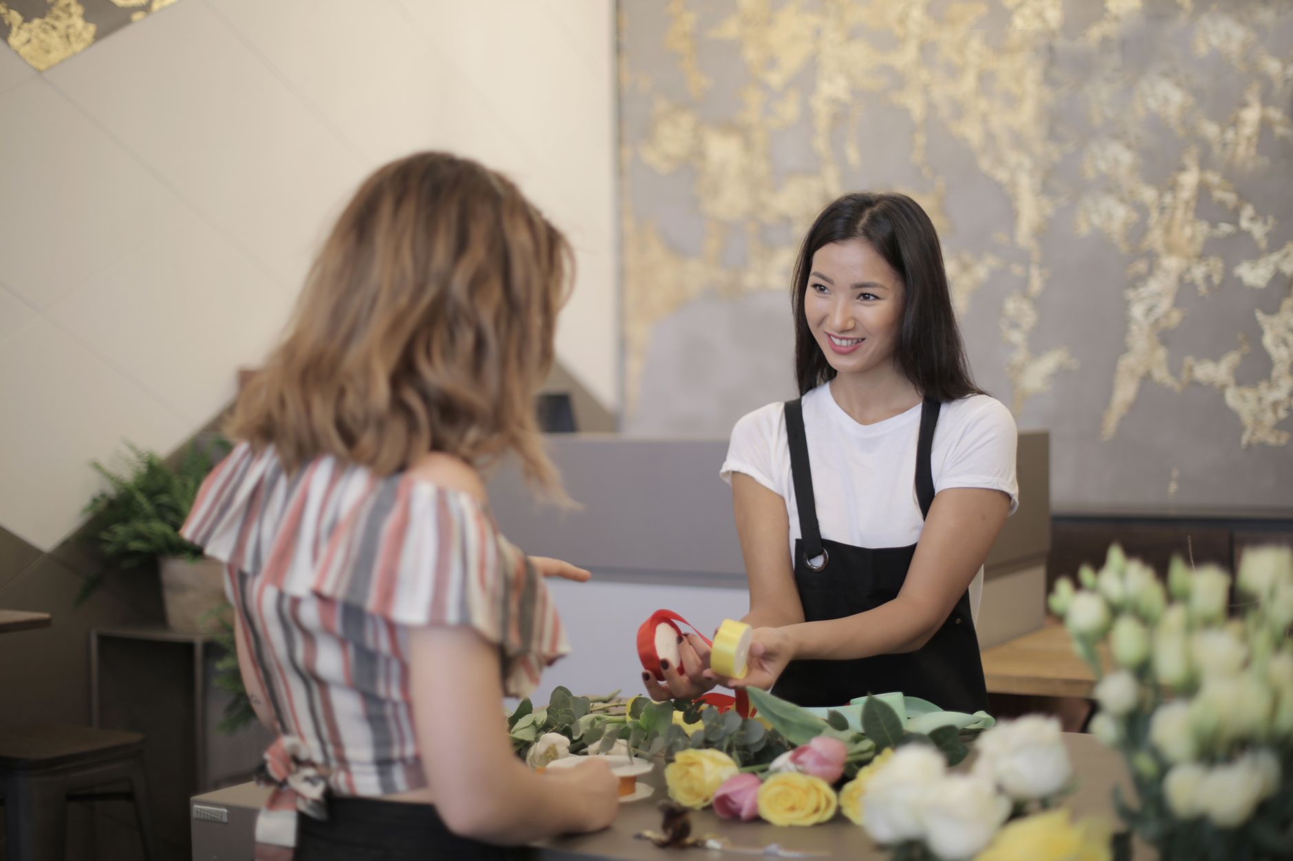 A smiling florist helping a customer choose flowers at a shop counter